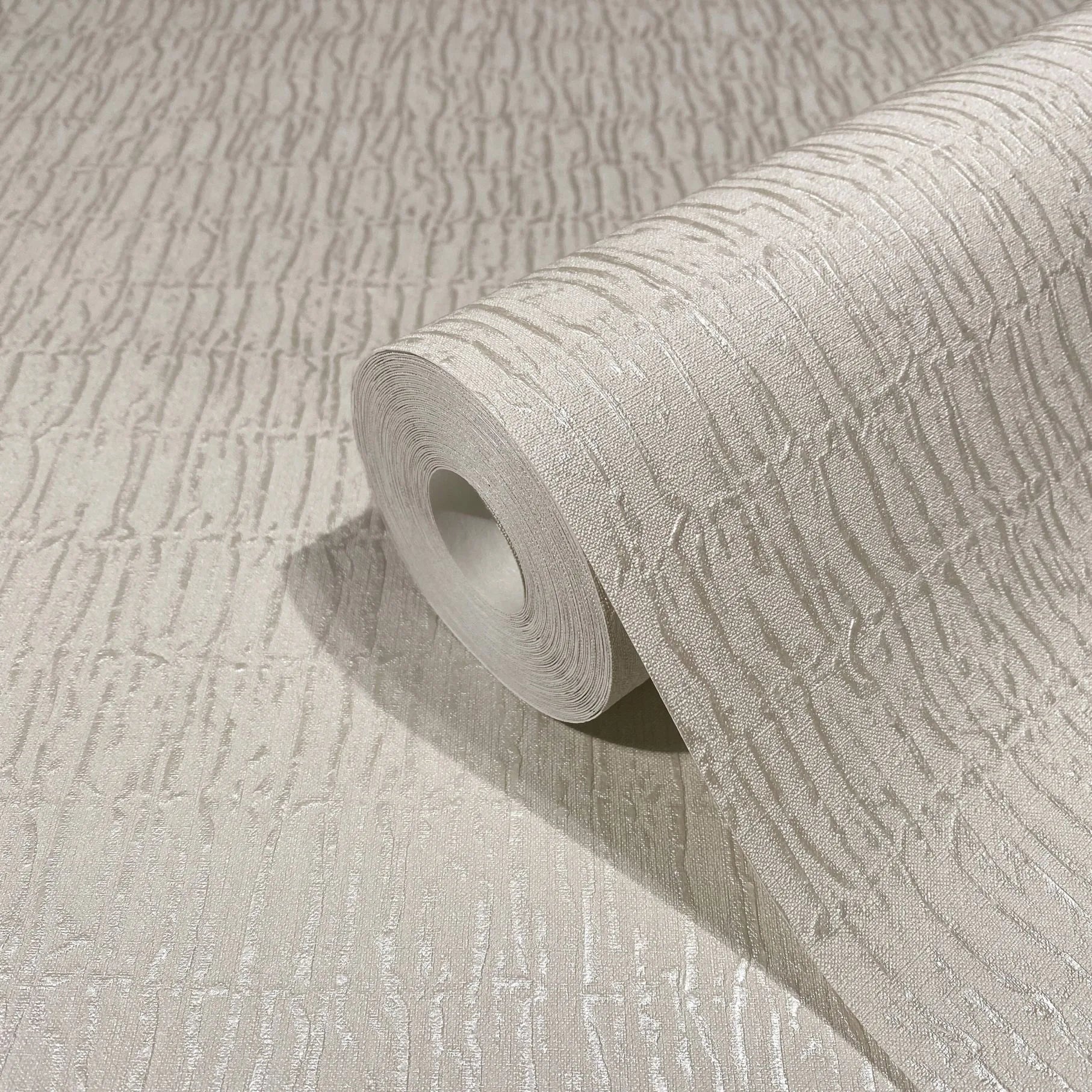 Marburg Kumano 34502 A beige wallpaper roll partially unrolled, showing a raised irregular vertical striation pattern with a subtle sheen.