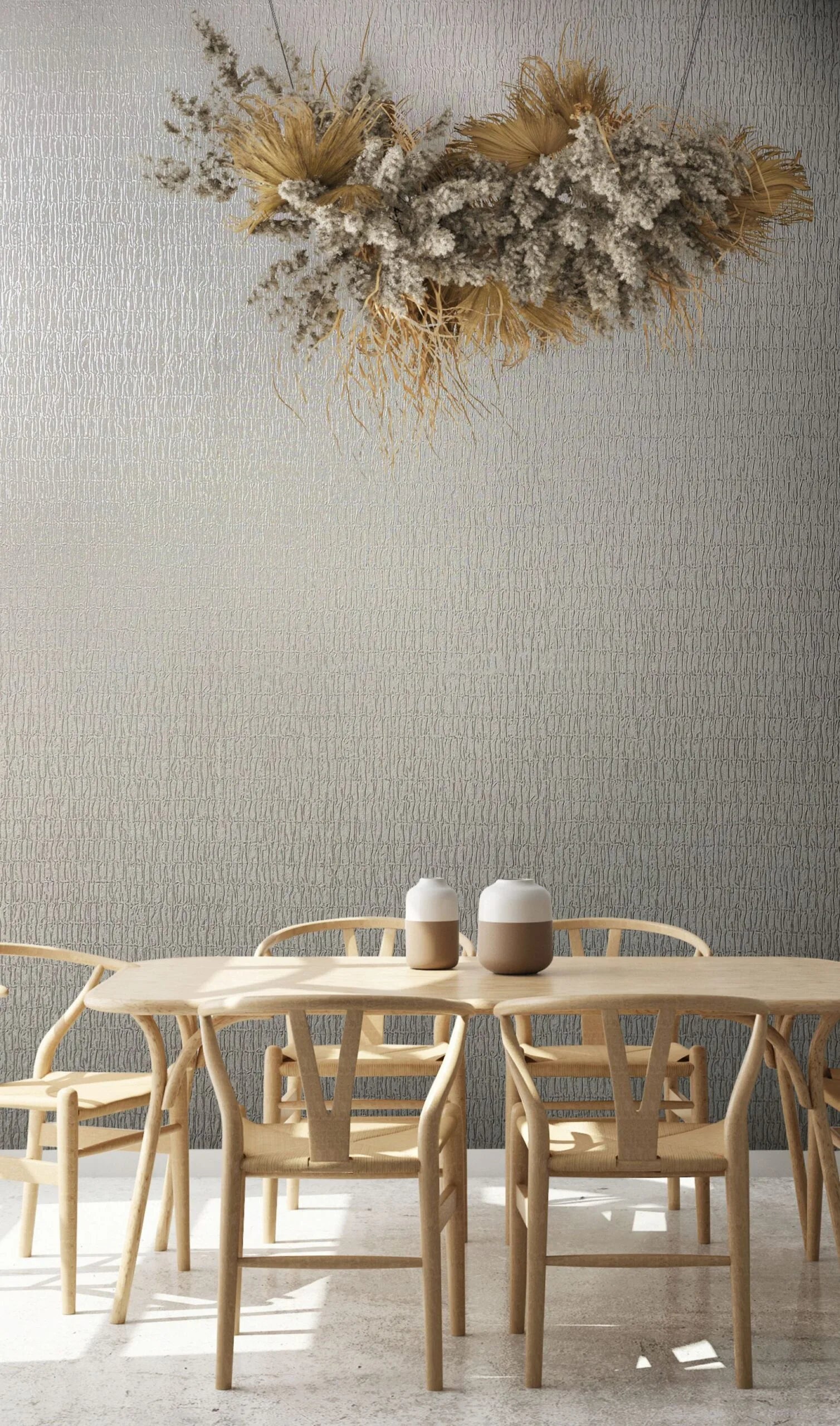 Marburg Kumano 34503 Gray textured wallpaper with irregular vertical lines behind a light wood dining table and chairs, two small ceramic jars on the table, and a hanging dried floral arrangement above.