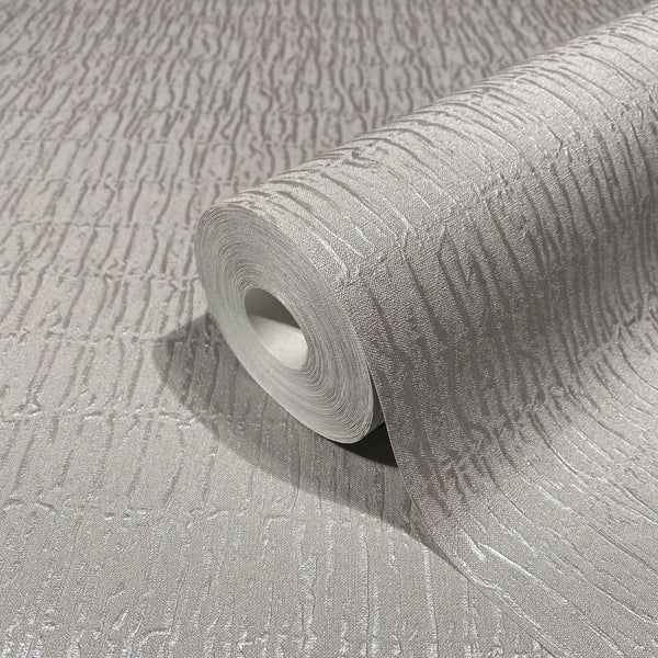 Marburg Kumano 34504 Close-up of a gray textured wallpaper with irregular vertical striations, shown partially unrolled with the roll resting on the matching surface.