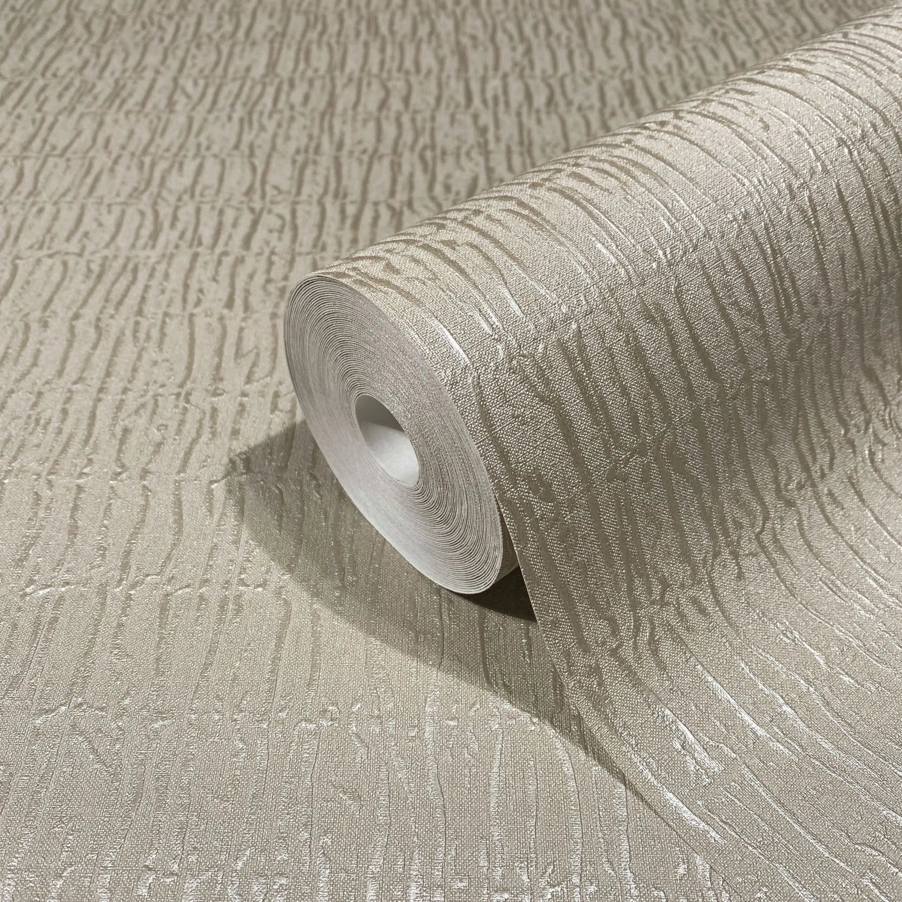 Marburg Kumano 34505 Close-up of a beige wallpaper roll with raised, irregular vertical lines, partially unrolled across the same patterned surface.
