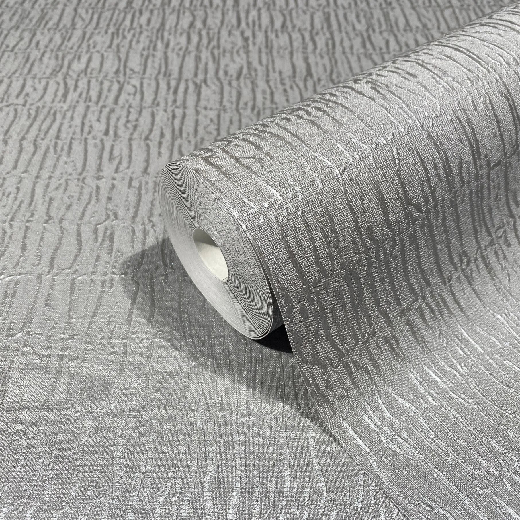 Marburg Kumano 34506 A gray wallpaper roll with raised irregular vertical striations, shown partially unrolled on a matching surface.