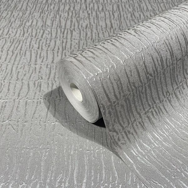 Marburg Kumano 34506 A gray wallpaper roll with raised irregular vertical striations, shown partially unrolled on a matching surface.