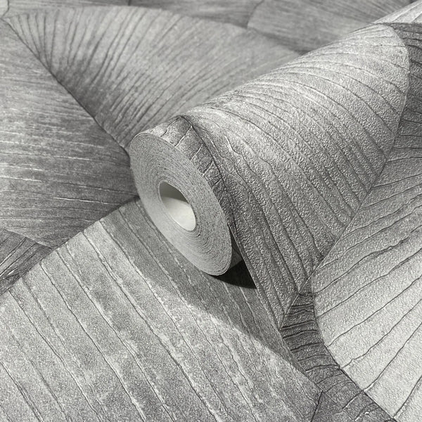 Marburg Kumano 34508 Close-up of a gray wallpaper roll resting on matching unrolled wallpaper, showing an organic wavy linear texture with fine striations.