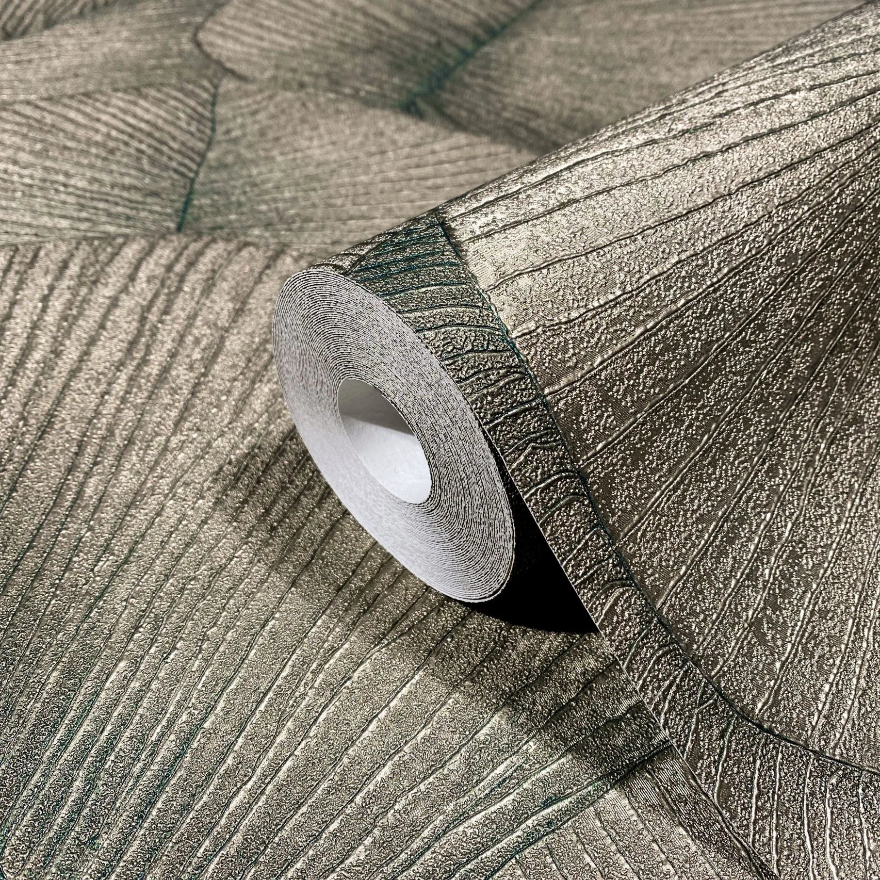 Marburg Kumano 34513 Close-up of a wallpaper roll resting on a matching sheet, showing a large leaf‑vein design with raised linear texture and a subtle sheen.