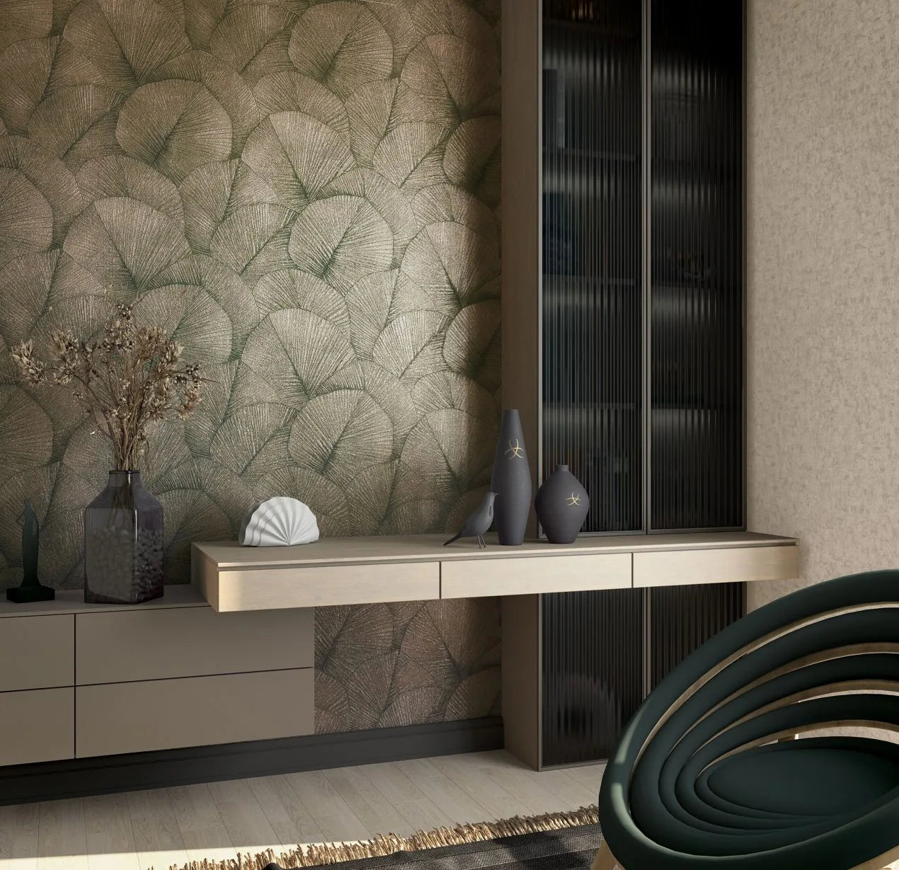 Marburg Kumano 34513 Leaf-pattern wallpaper in green and gold shown as a feature wall behind a floating sideboard with decorative vases, a shell object, dried branches in a glass vase, and a ribbed-glass cabinet, with a sculptural dark green chair in the foreground.