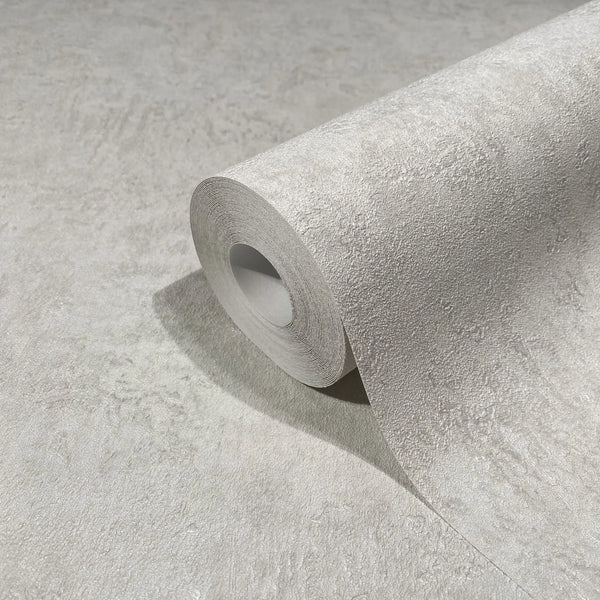 Marburg Kumano 34519 Close-up of a gray textured wallpaper roll resting on matching unrolled wallpaper, showing an irregular stucco-like surface.