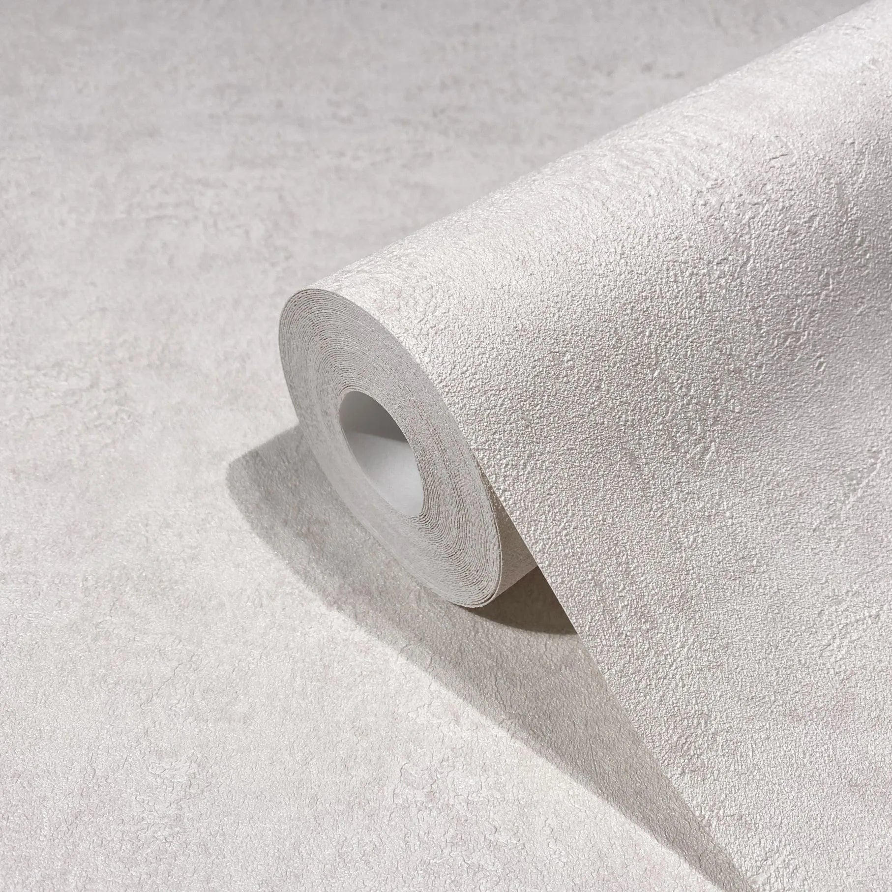Marburg Kumano 34521 Close-up of a textured wallpaper roll resting on a matching unrolled sheet in a light tone.