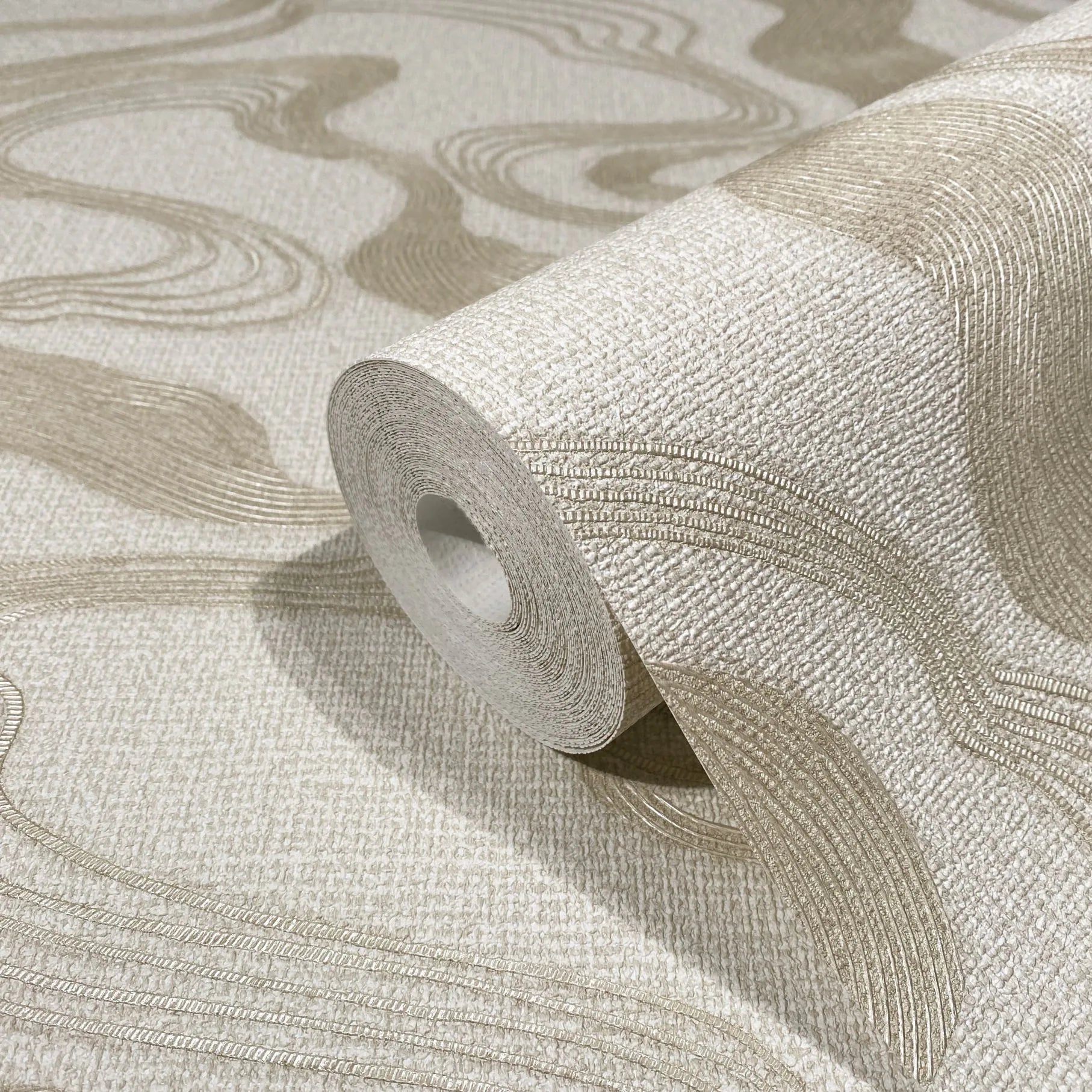 Marburg Kumano 34535 Close-up of a wallpaper roll on matching unrolled sheet, showing a light textured background with raised beige wavy lines.