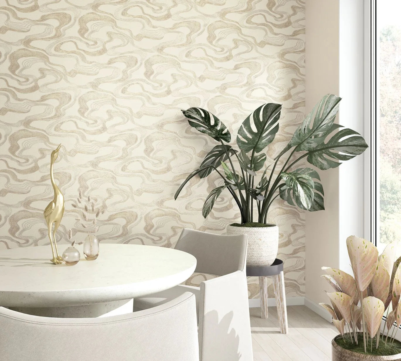 Marburg Kumano 34535 Beige abstract wavy pattern wallpaper behind a round white dining table with upholstered chairs, a brass bird figurine, small glass vases, and a large potted monstera beside a window.