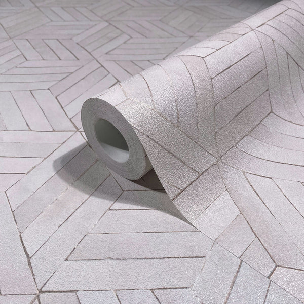 Marburg Leyla 81699 A close-up of a wallpaper roll resting on matching unrolled wallpaper with a light gray, textured geometric chevron pattern that forms radiating shapes.