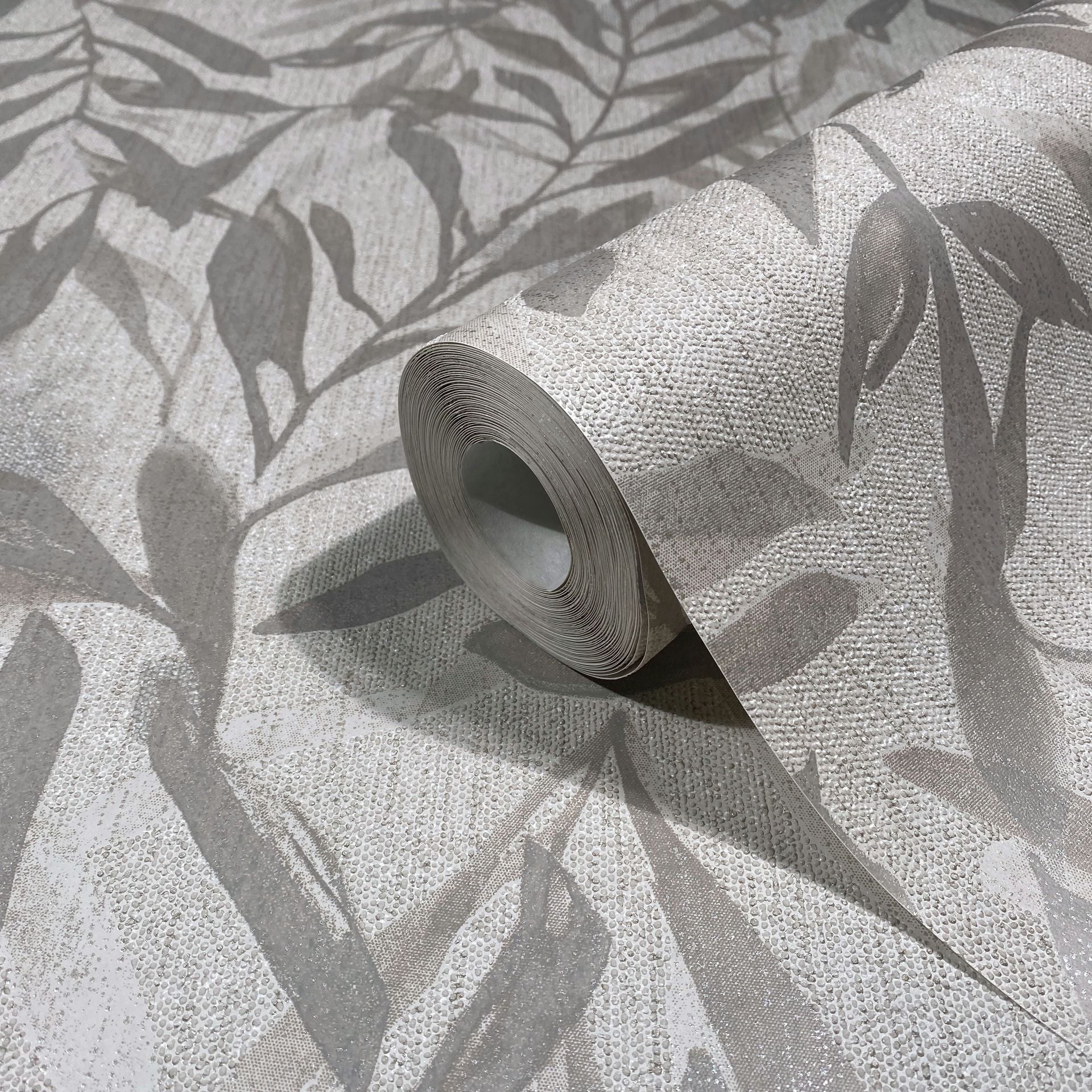 Marburg Leyla 82440 Wallpaper roll on a matching unrolled sheet featuring a beige and gray leafy design with a raised dotted texture.