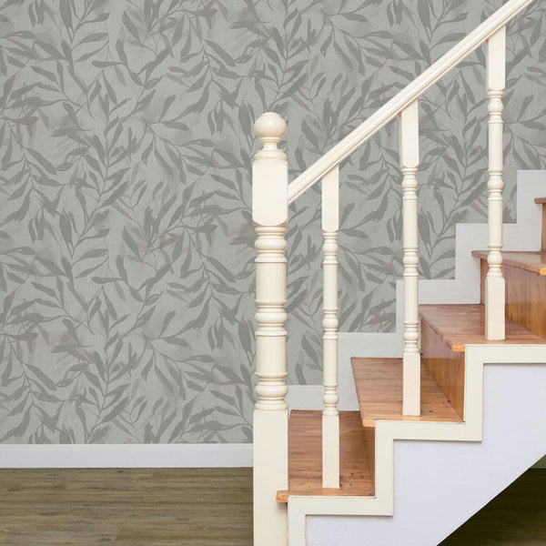 Marburg Leyla 82440 Gray-beige leaf pattern wallpaper behind a wooden staircase with white balusters and handrail.