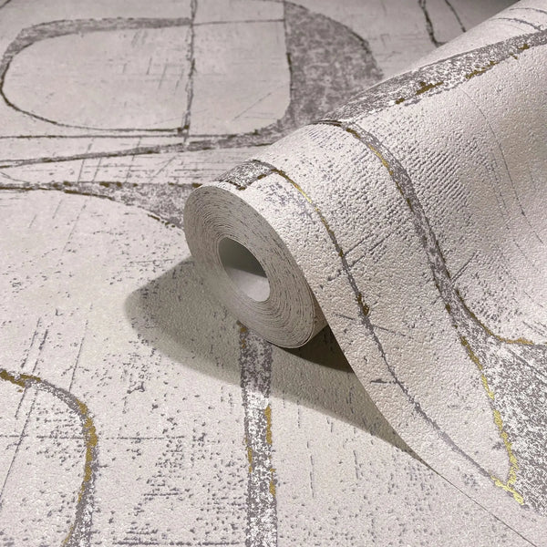 Marburg Leyla 82453 Rolled wallpaper resting on a matching unrolled sheet, showing a textured light beige surface with abstract intersecting gray lines and thin gold accents.