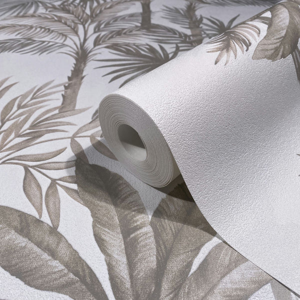 Marburg Leyla 82454 Close-up of a textured white wallpaper roll resting on an unrolled wallpaper showing beige palm leaves and trunks on a white background.