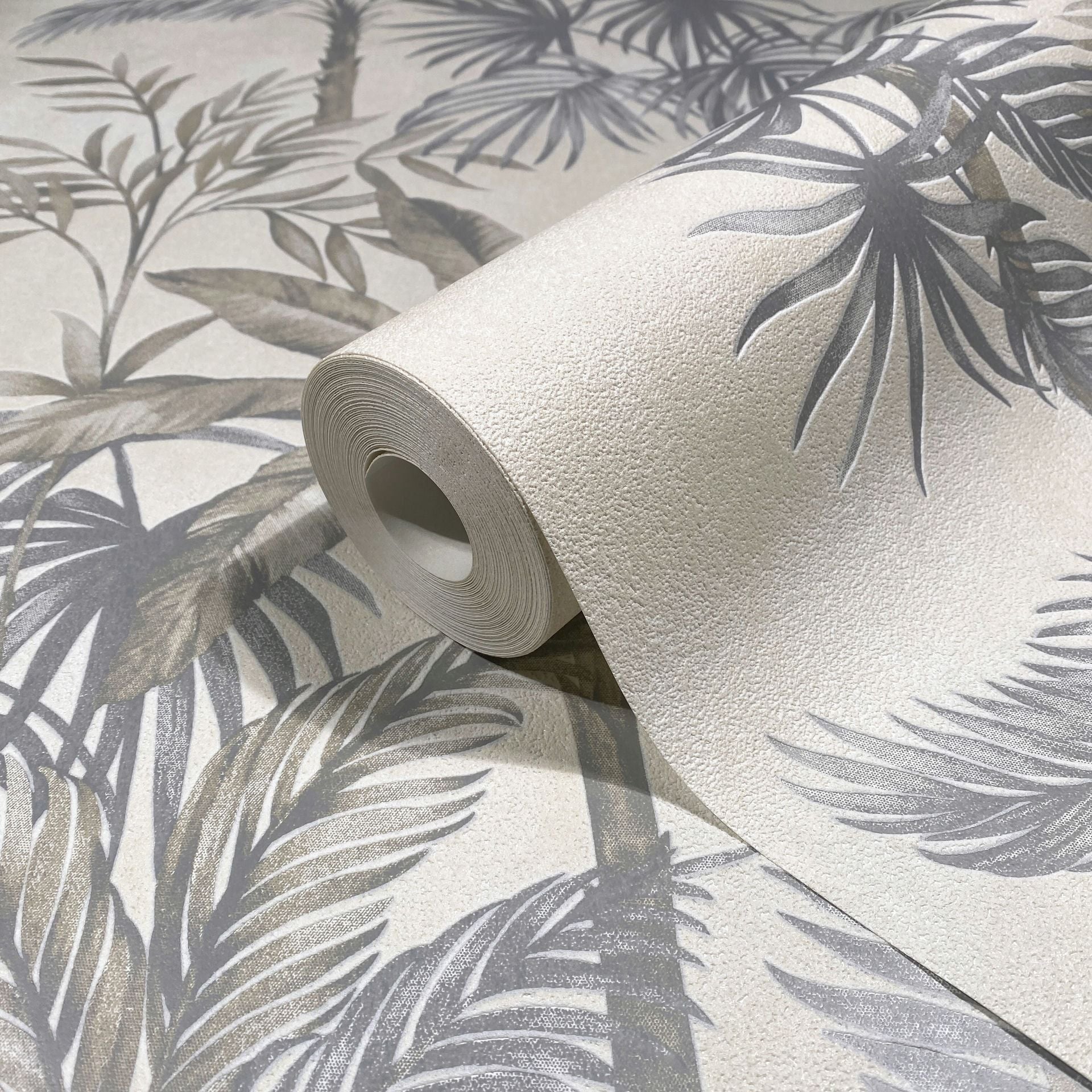 Marburg Leyla 82455 Partially unrolled wallpaper roll showing a textured beige background with gray palm leaf pattern.
