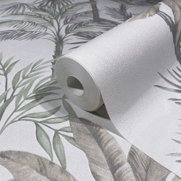 Marburg Leyla 82457 Close-up of a wallpaper roll resting on matching wallpaper with a tropical leaf motif in green and gray on a light textured background.