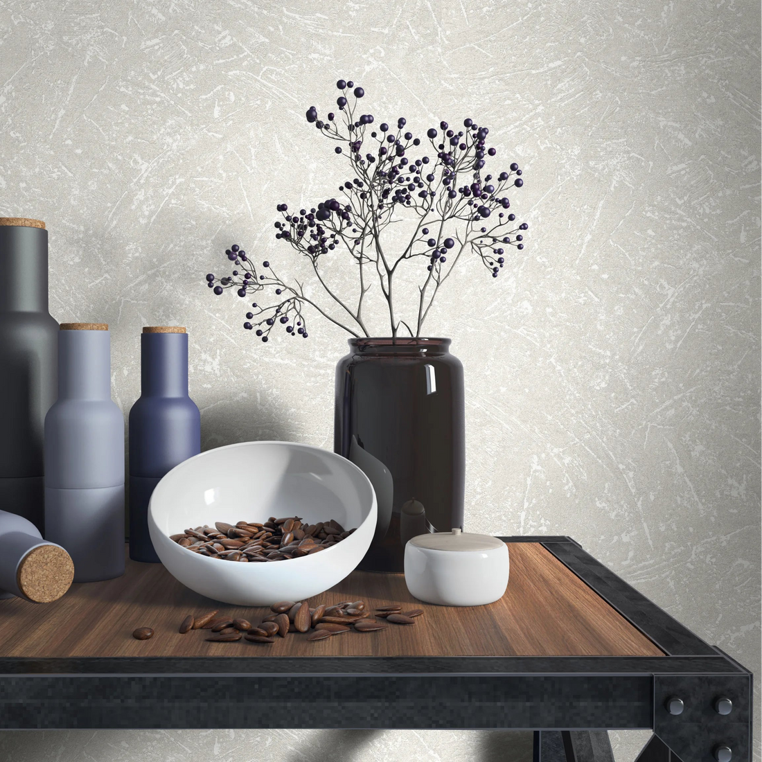 Marburg Loft Superior 34152 Light beige‑gray textured wallpaper with subtle abstract scratch lines behind a wood‑and‑metal table styled with matte bottles, a dark vase holding berry branches, a white bowl filled with beans, and a small lidded jar.
