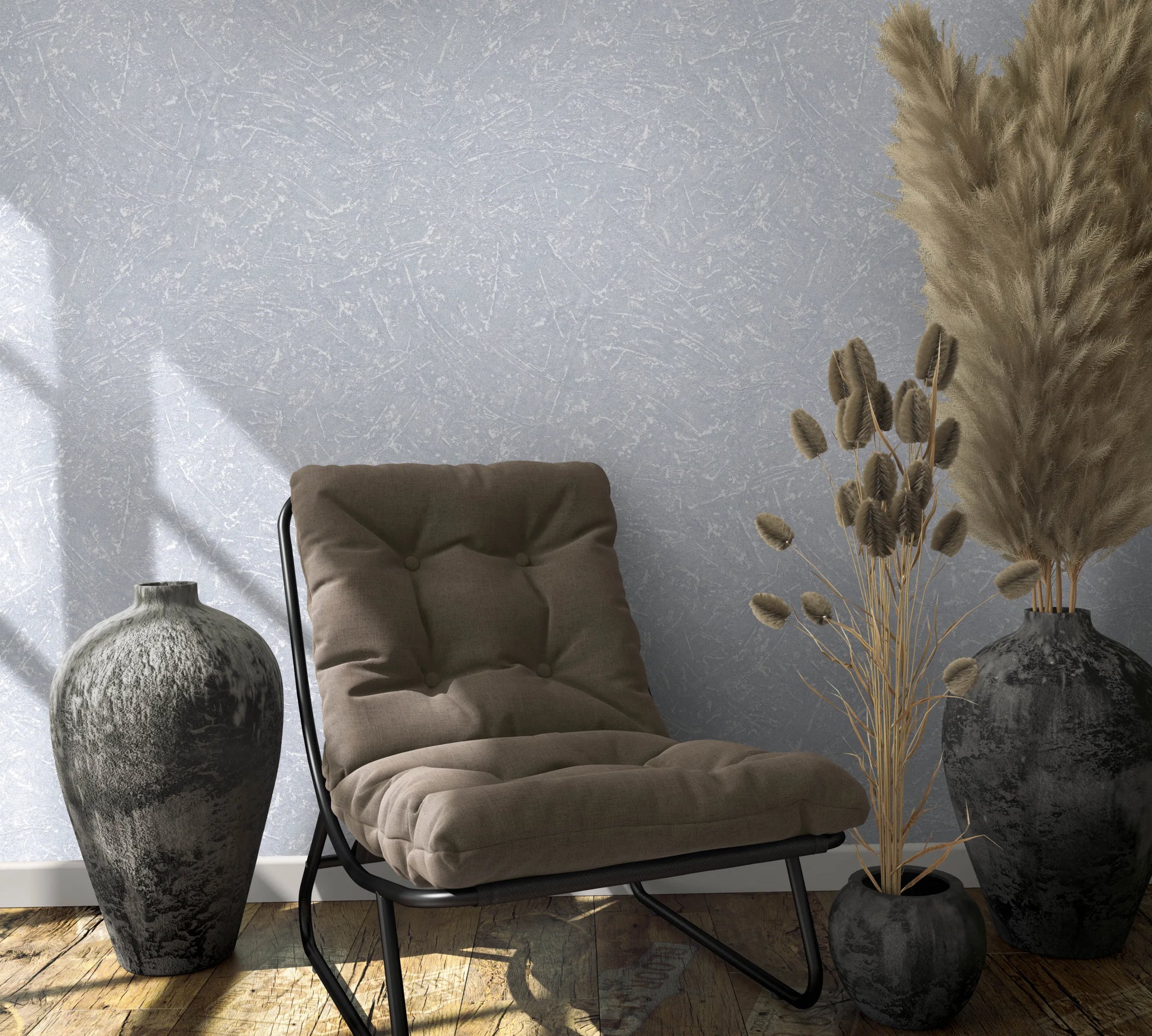 Marburg Loft Superior 34153 Gray wallpaper with an abstract scratch texture shown behind a cushioned lounge chair, two dark vases, a small pot with dried grasses, and wood plank flooring.
