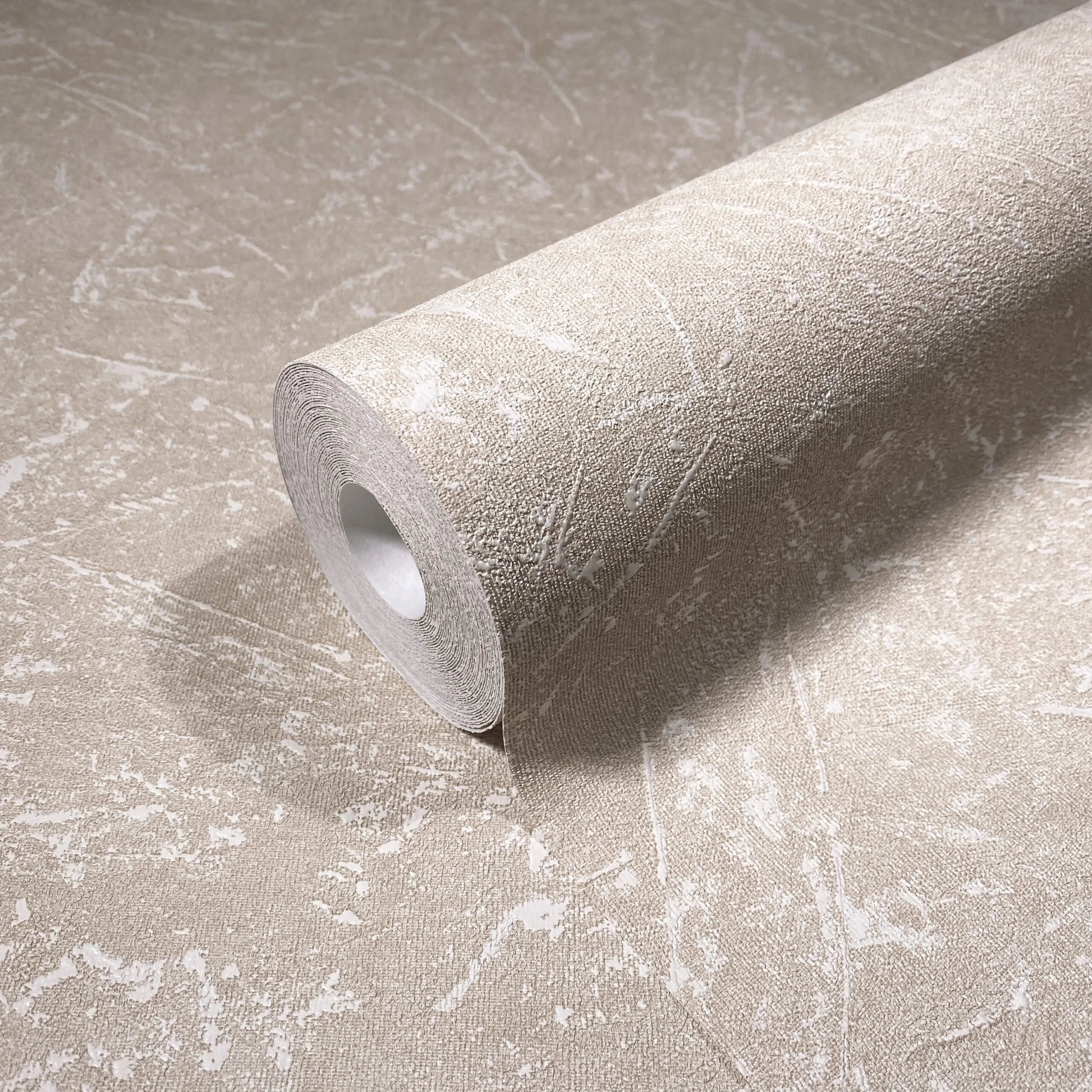 Marburg Loft Superior 34154 Beige textured wallpaper roll with irregular white distressed markings, shown resting on a matching unrolled sheet.