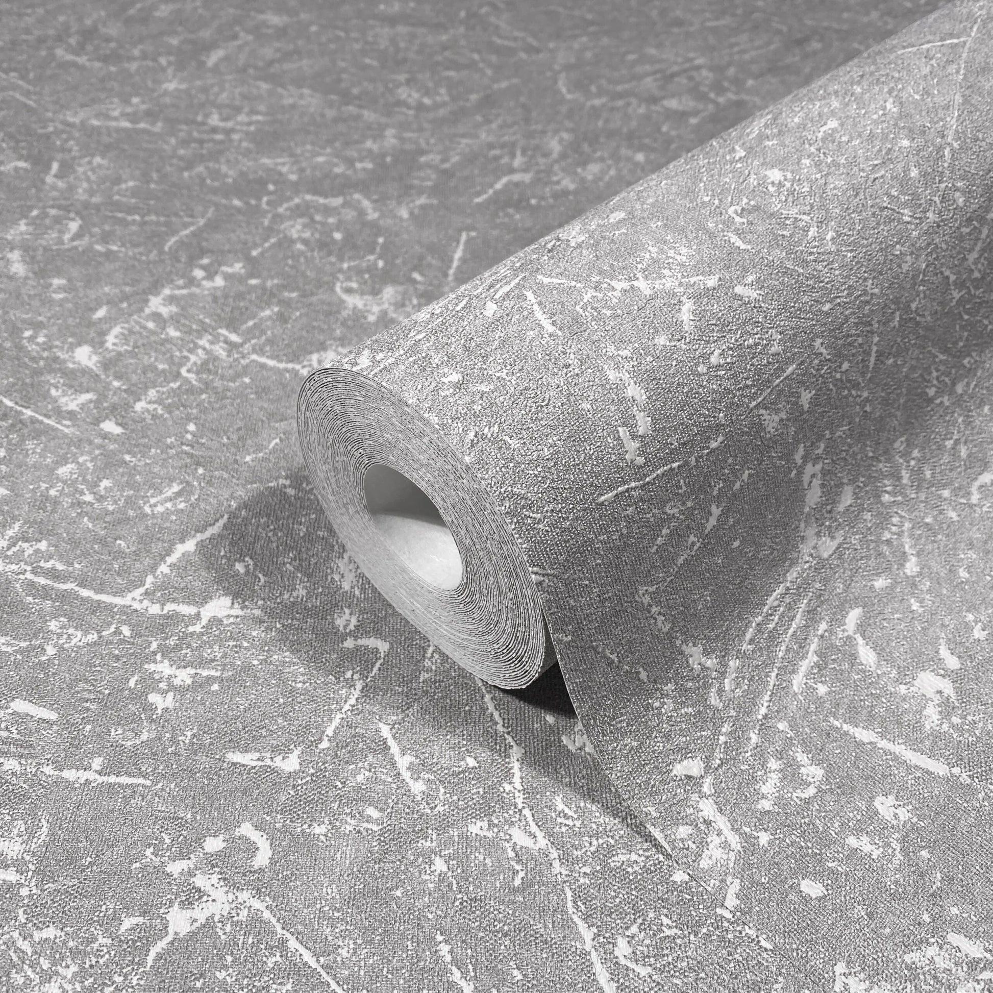 Marburg Loft Superior 34155 Close-up product photo of a wallpaper roll with a gray, distressed marbled pattern, partially unrolled on the same wallpaper.