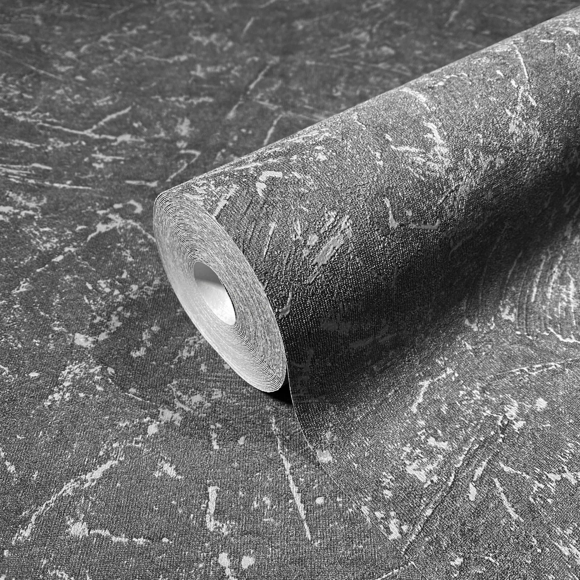 Marburg Loft Superior 34156 Angled wallpaper roll resting on the same design, showing a dark grey abstract textured pattern with lighter streaks and patches.