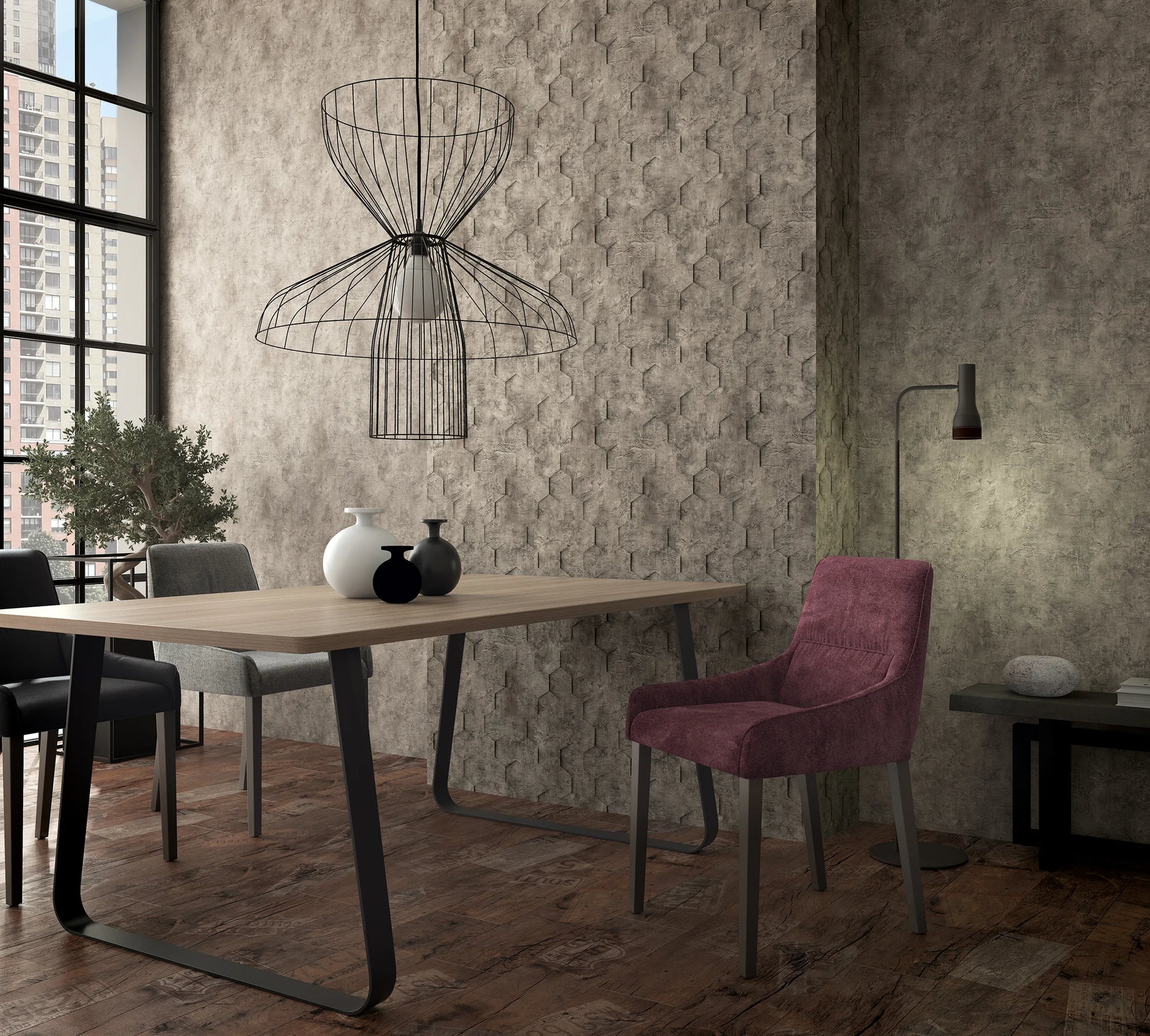 Marburg Loft Superior 34162 Dining room scene featuring a brown hexagon‑textured wallpaper as a feature wall behind a wood table with vases, upholstered chairs, a wireframe pendant light, and a floor lamp beside a large window with city view.
