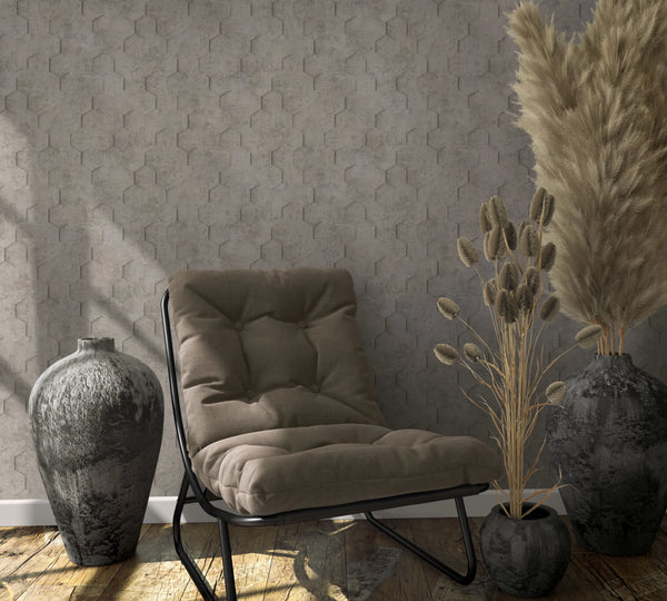 Marburg Loft Superior 34162 Tone-on-tone hexagon geometric wallpaper behind a cushioned lounge chair with ceramic vases and dried grasses on a wood plank floor.