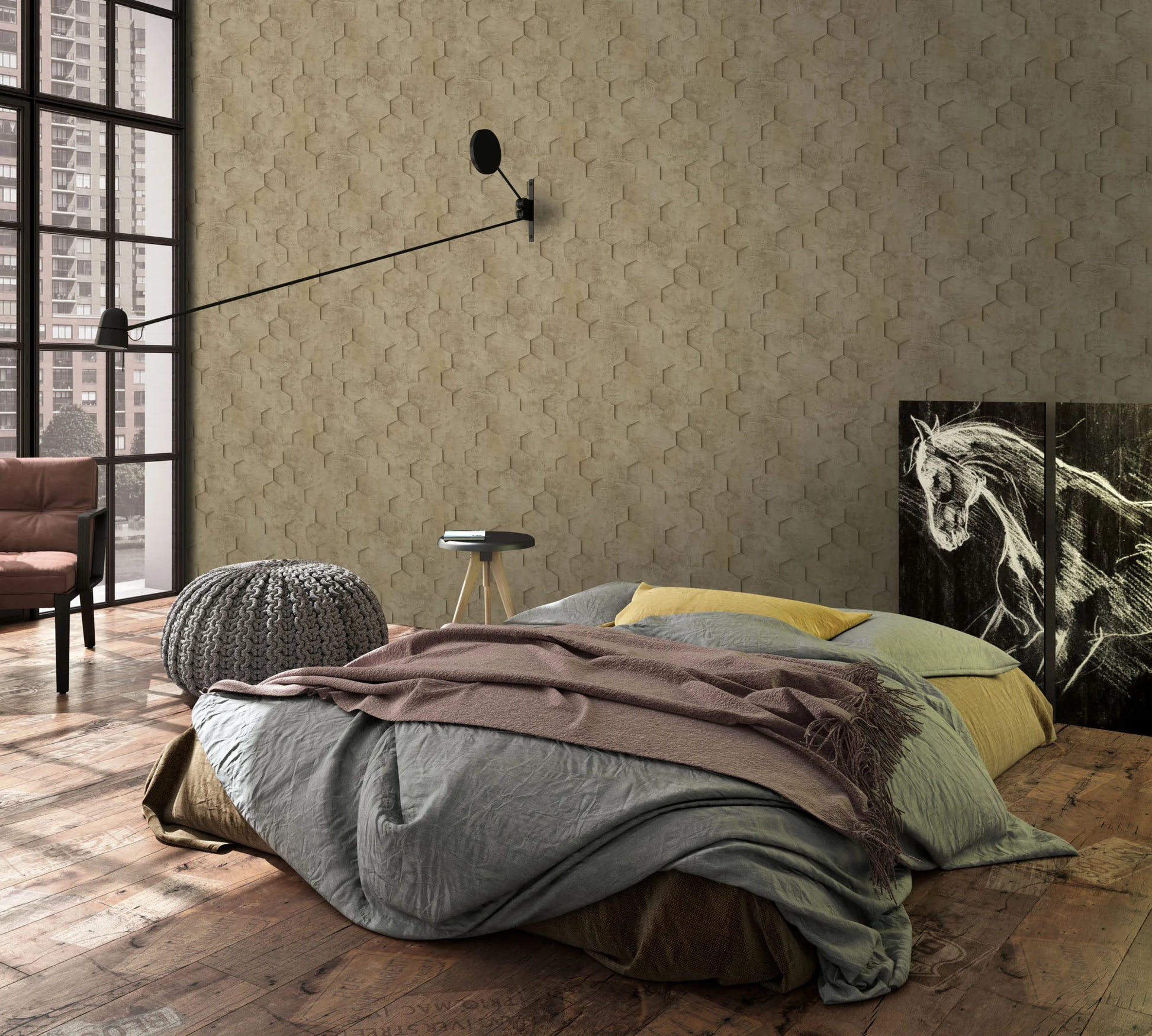 Marburg Loft Superior 34163 Bedroom scene with taupe hexagon-pattern wallpaper. A low bed with layered bedding sits on a rustic wood floor beside a knitted pouf, small stool table, and armchair, with a long swing-arm wall lamp, large window, and a horse art panel leaning against the wall.