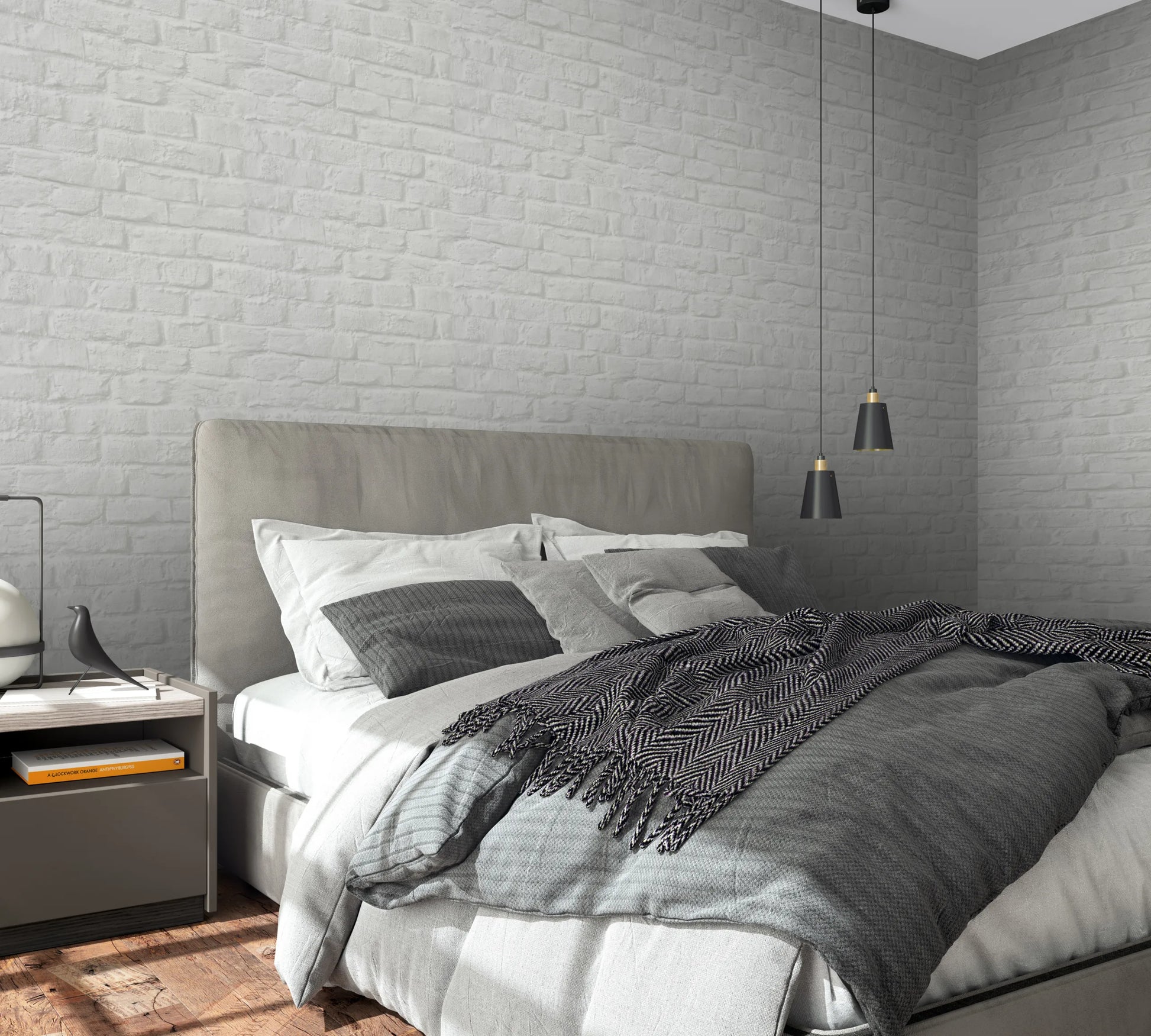 Marburg Loft Superior 34166 Bedroom scene featuring light gray brick-effect wallpaper on two walls behind a bed with gray bedding, two black pendant lights, and a nightstand with a book and a small bird figurine.
