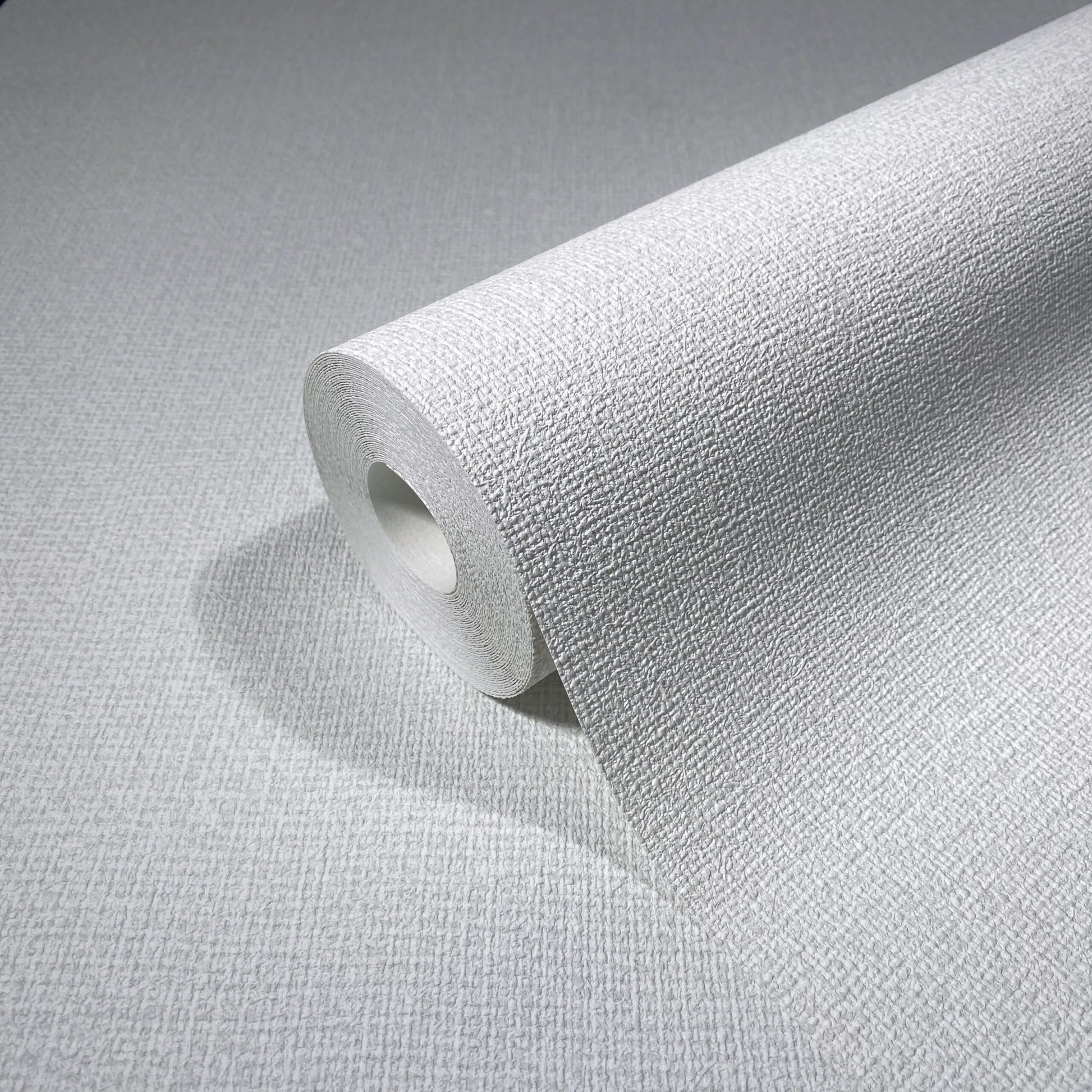 Marburg Loft Superior 34171 Close-up of a white textured wallpaper roll showing a fine crosshatch grid on a matching unrolled sheet.