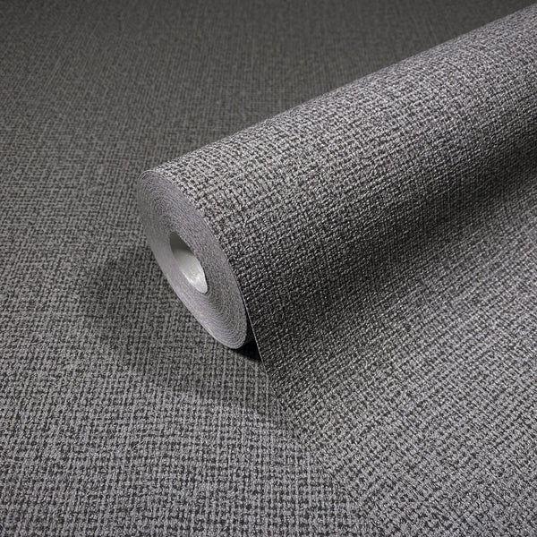 Marburg Loft Superior 34174 Angled roll of gray textured wallpaper with a small crosshatch grid, shown on a matching unrolled surface.