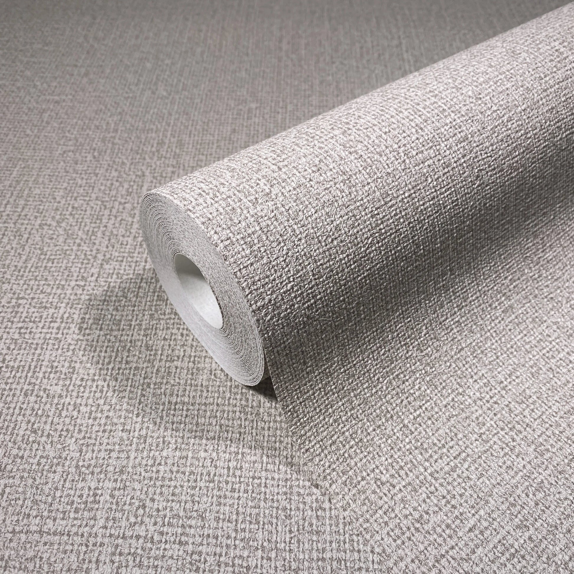 Marburg Loft Superior 34176 Close-up of a wallpaper roll with a textured crosshatch pattern resting on matching unrolled wallpaper.