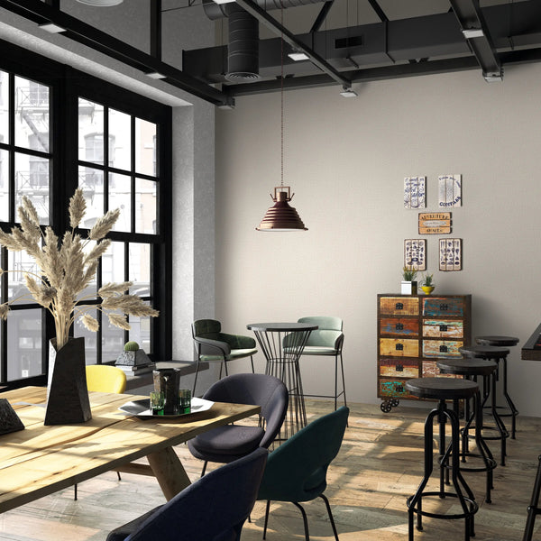 Marburg Loft Superior 34177 Industrial-style cafe interior showing a beige textured wallpaper feature wall, a hanging pendant light, bar stools at a counter, mixed chairs and tables, a colorful drawer cabinet with small wall art, and large black-framed windows.
