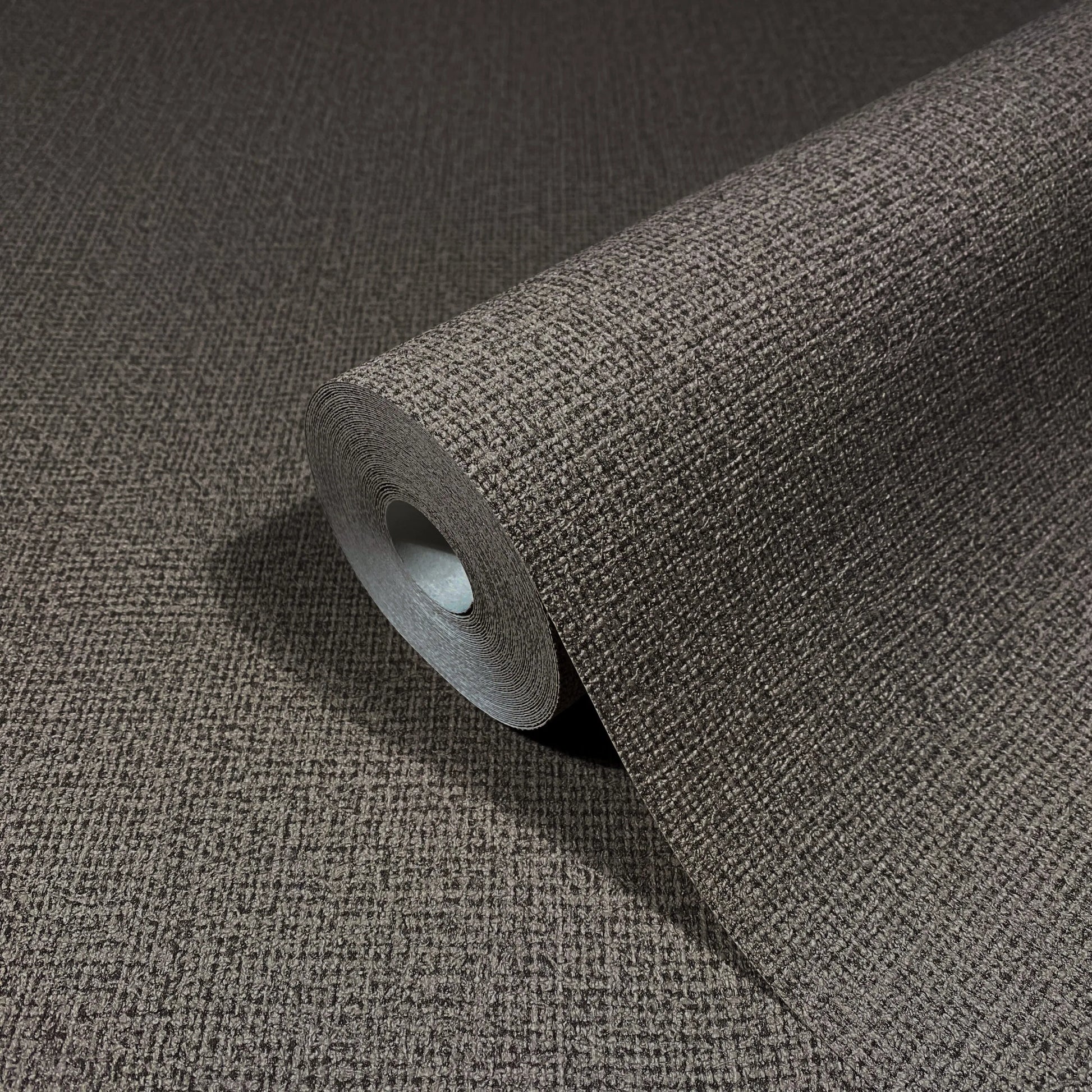 Marburg Loft Superior 34183 Roll of brown textured wallpaper with a small-scale grid surface, partially unrolled on the same material.