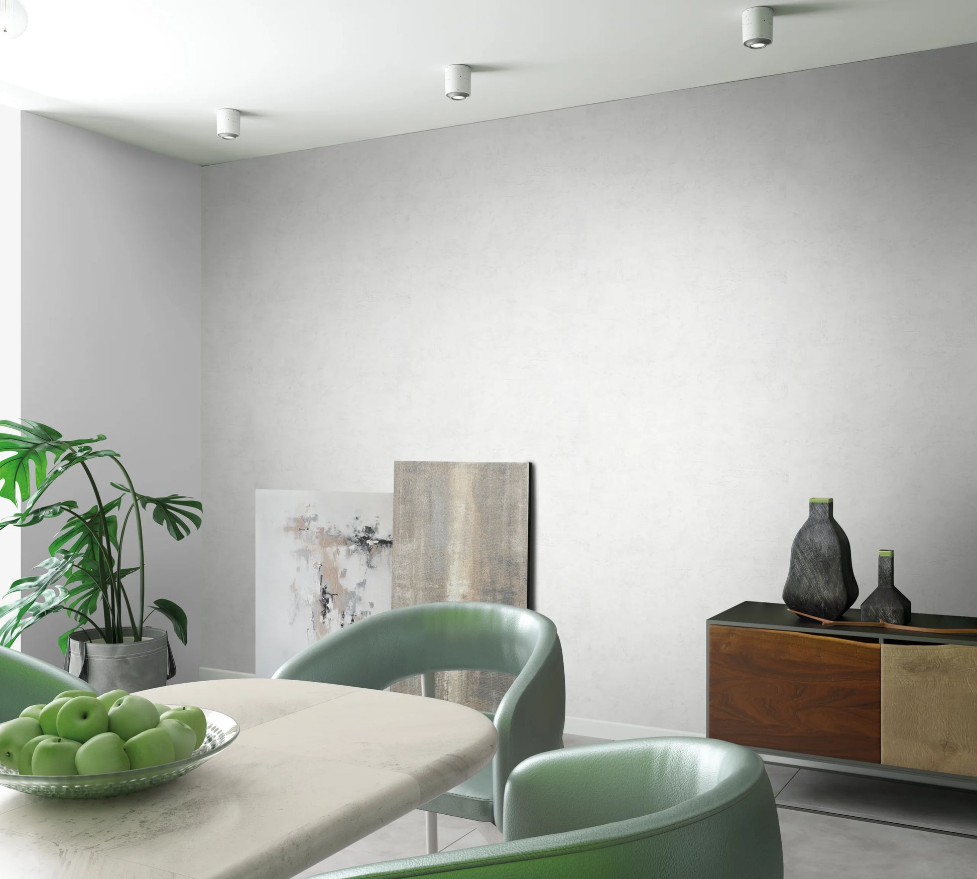 Marburg Loft Superior 34184 Light, subtly textured wallpaper on a dining room wall with a table holding a bowl of green apples, green chairs, a sideboard with two decorative vessels, a potted plant, leaning art panels, and ceiling spotlights.