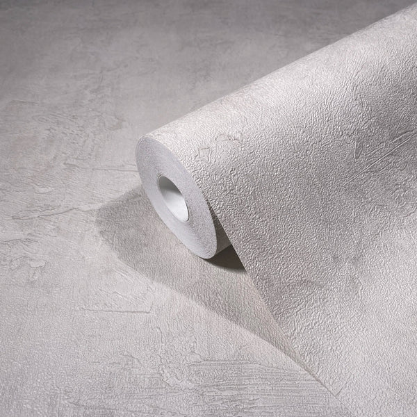 Marburg Loft Superior 34186 Angled roll of light neutral textured wallpaper with a subtle plaster effect, partially unrolled on a matching surface.