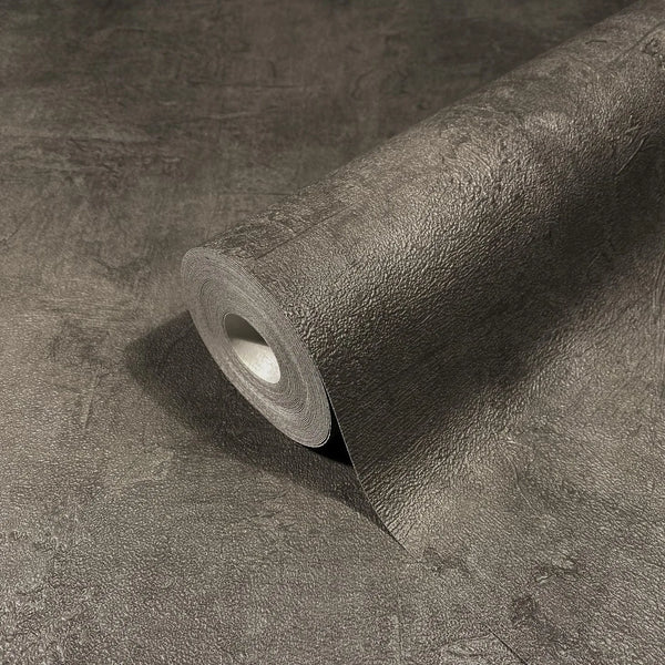 Marburg Loft Superior 34188 A textured dark brown wallpaper roll partially unrolled across the same wallpaper, showing a plaster-like surface pattern.