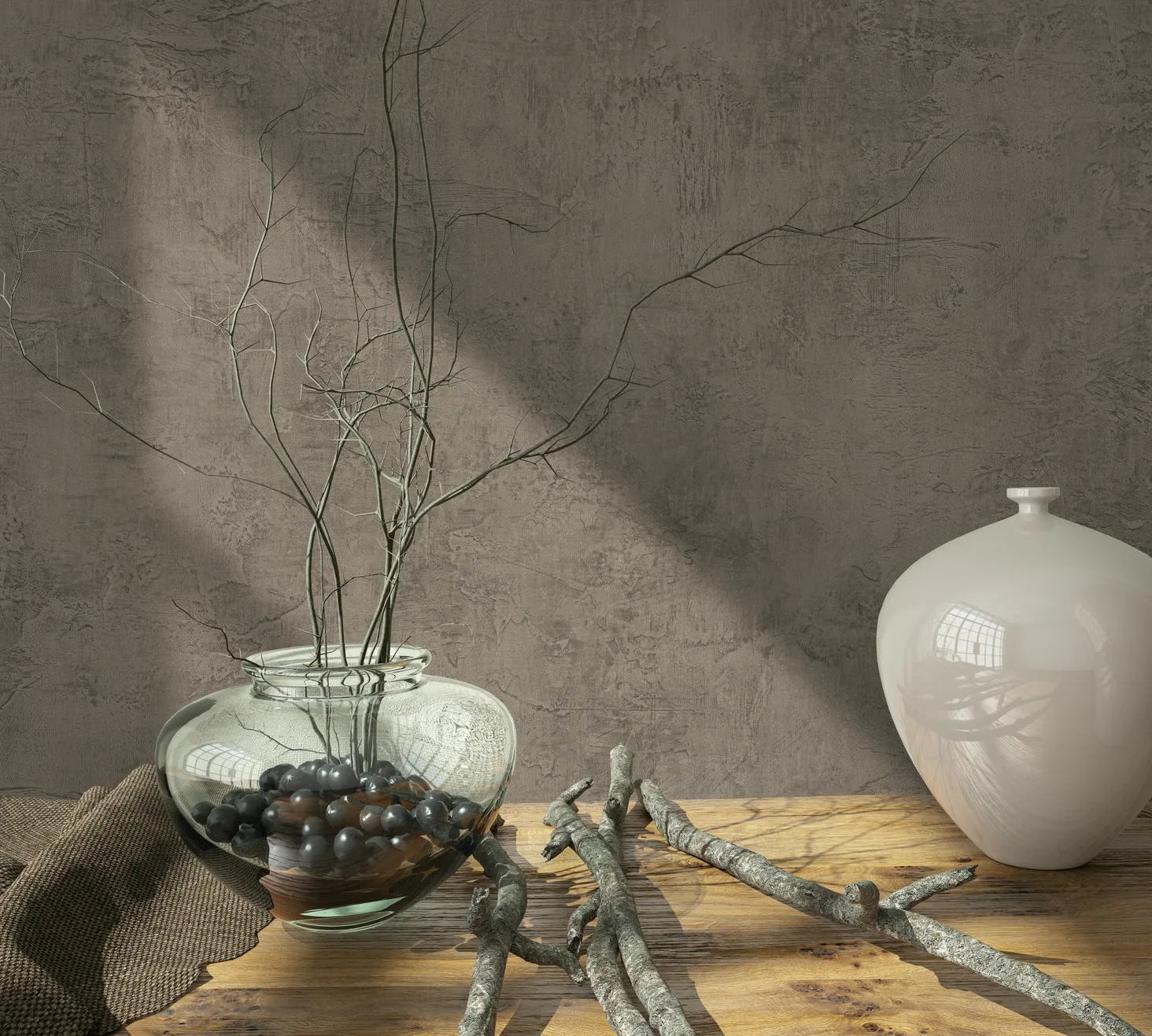 Marburg Loft Superior 34188 Textured brown wallpaper with a plaster-like look behind a wooden table styled with a clear glass vase of twigs, a white ceramic vase, loose branches, and a cloth.