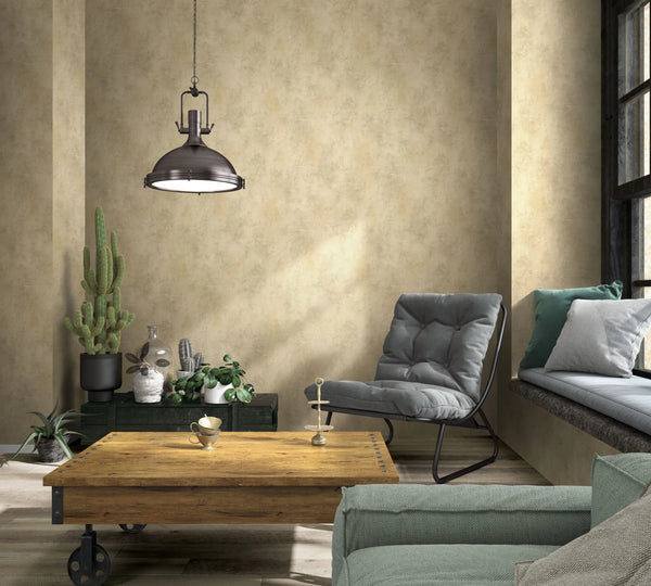 Marburg Loft Superior 34190 Living room with warm beige mottled wallpaper. An industrial pendant hangs above a wood coffee table on casters, with a gray lounge chair, window bench with cushions, a sofa corner, and several potted plants including cacti near a window.