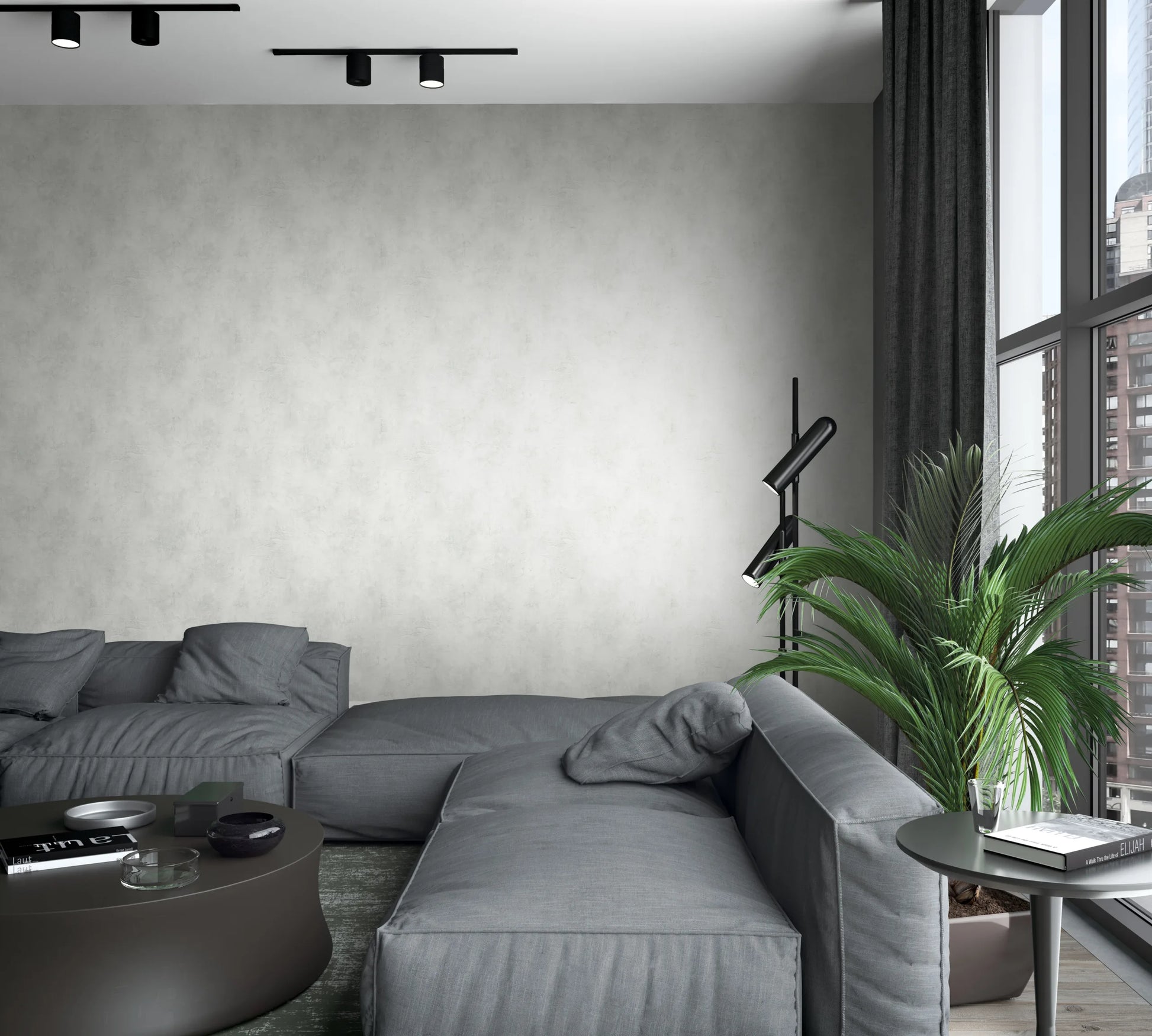 Marburg Loft Superior 34192 Light gray mottled wallpaper on a living room wall behind a low gray sectional sofa, with a round coffee table, side table with books, a black floor lamp, a potted palm, tall windows with dark curtains, and ceiling spotlights.