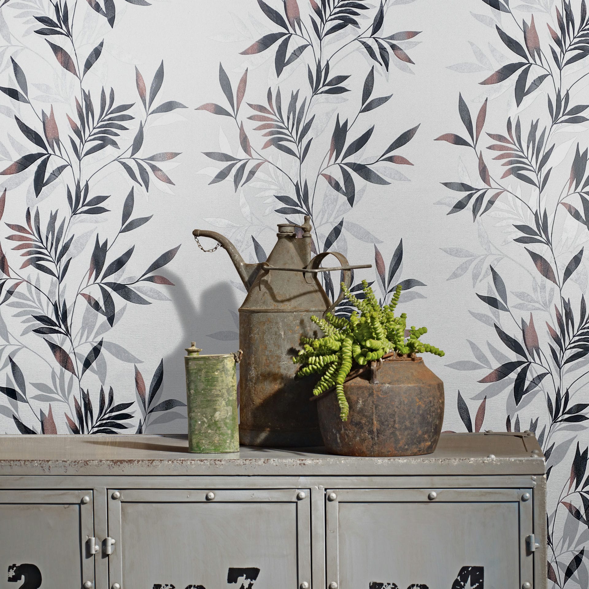 Marburg Mona 82458 Black, gray, and muted pink leafy wallpaper behind an industrial metal cabinet topped with a vintage metal can, a small green canister, and a potted plant.
