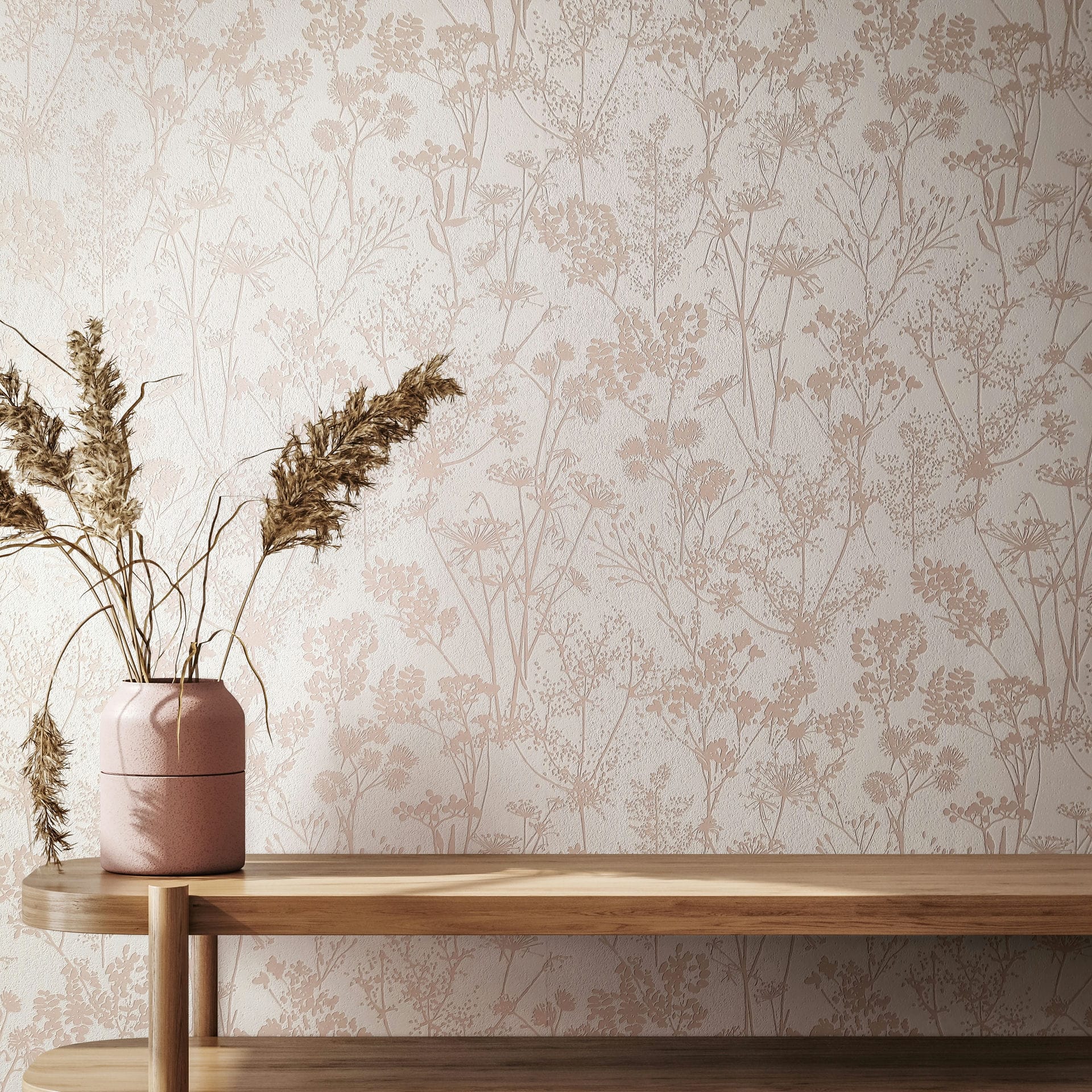Marburg Mona 82463 Beige floral silhouette wallpaper on a white wall behind a light wood console with a pink vase holding dried grasses.