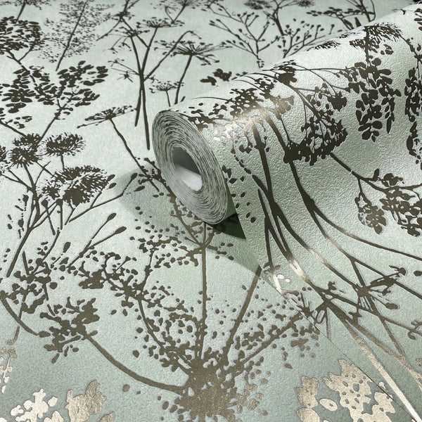 Marburg Mona 82465 Close-up of a wallpaper roll showing metallic gold botanical silhouettes on a pale green textured background, with the pattern unrolled beneath it.