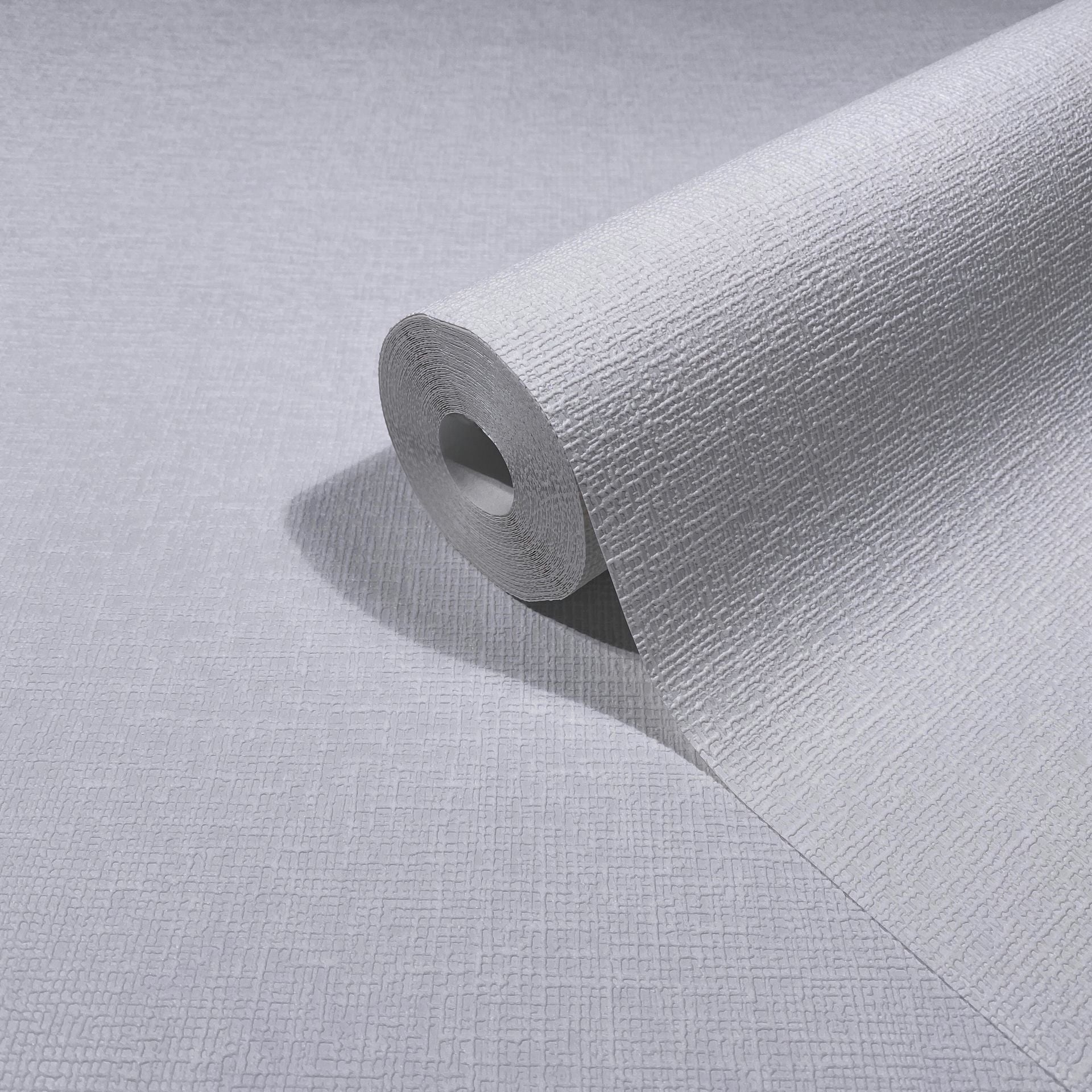 Marburg Mona 82473 Close-up of a white textured wallpaper roll partially unrolled, showing a fine crosshatch embossing.