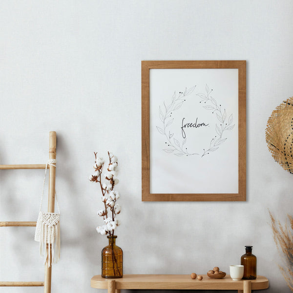 Marburg Mona 82473 Soft white wallpaper with a fine linen-style texture shown behind a wood-framed art print, a wooden ladder with a macrame bag, a light wood console with amber glass bottles—one holding cotton stems—a small white cup, scattered nuts, and a woven hat on the wall.