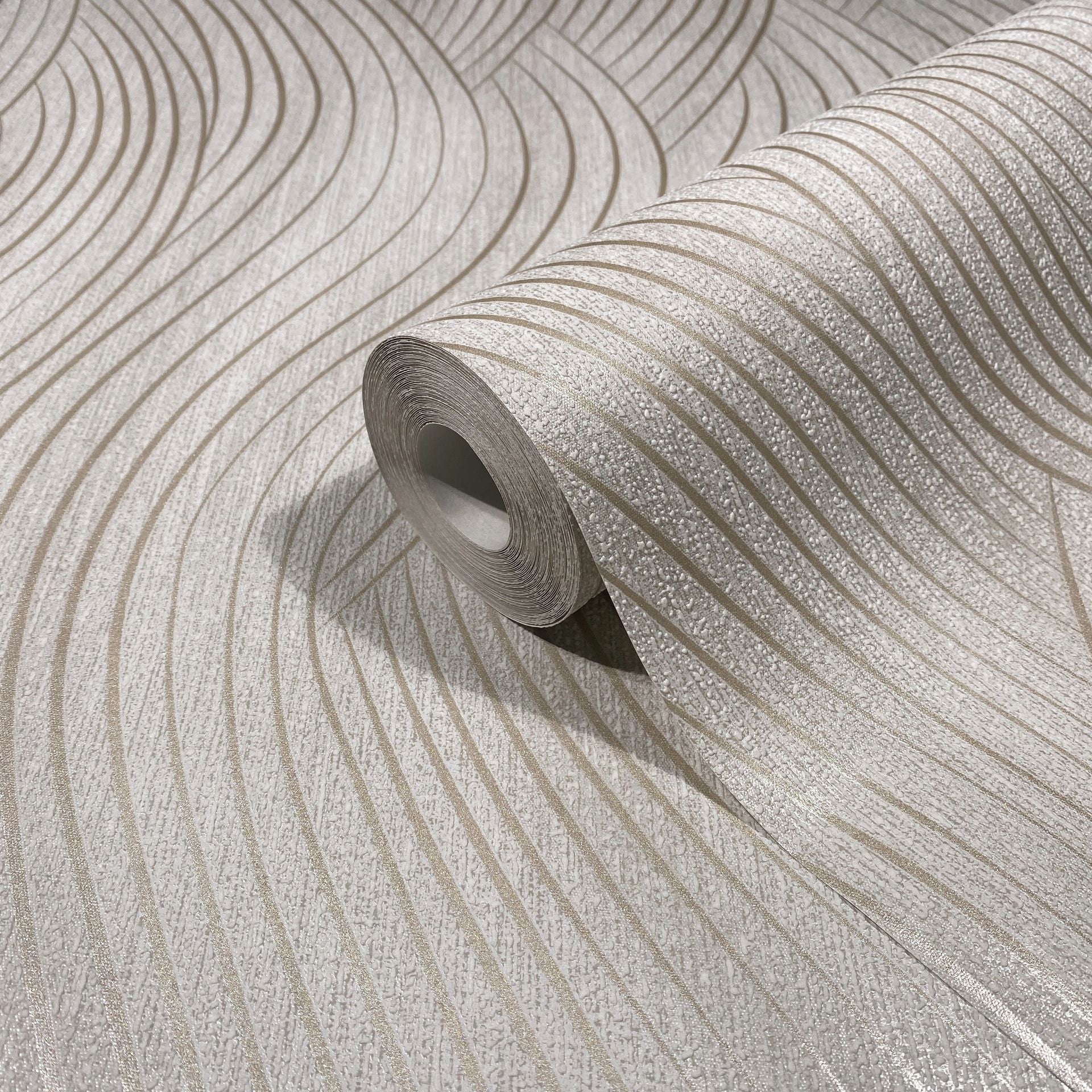 Marburg Mona 82475 A wallpaper roll resting on matching material shows a textured wavy stripe pattern in beige and light gray.