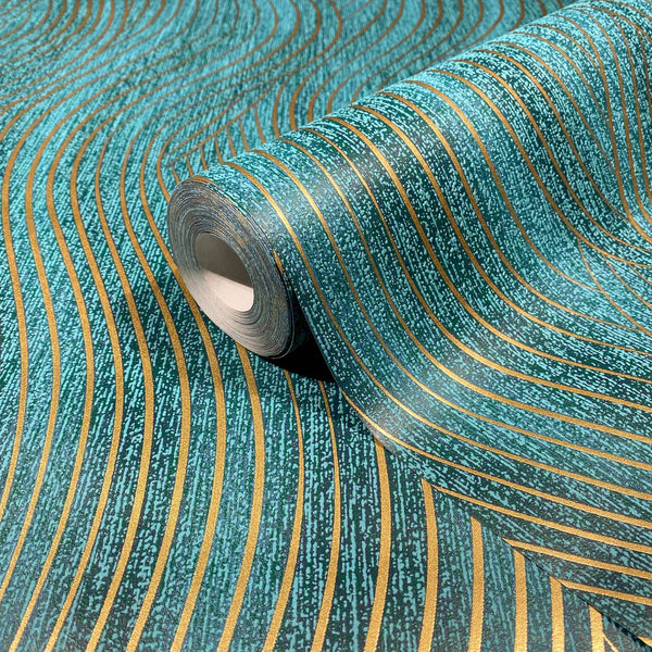 Marburg Mona 82477 Close-up of a wallpaper roll with a teal green background and flowing gold wavy stripes, shown resting on the same patterned sheet.