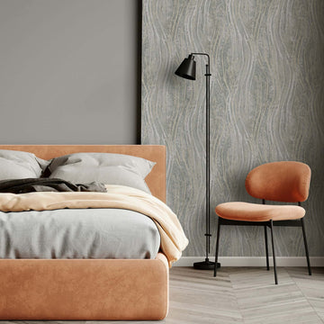 Marburg Naomi 82494 Bedroom scene showing a gray wallpaper with flowing wavy vertical lines on a feature wall, alongside an upholstered bed, a black floor lamp, and an armless chair.