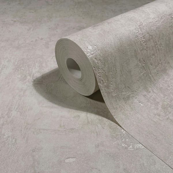 Marburg Naomi 82500 Close-up of a gray textured wallpaper roll partially unrolled on a matching surface, showing an abstract plaster-like pattern with a soft sheen.