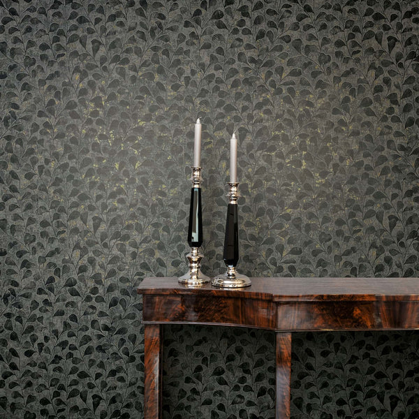 Marburg Naomi 82503 Dark gray leafy-pattern wallpaper behind a wood console table with two tall candlesticks and taper candles.
